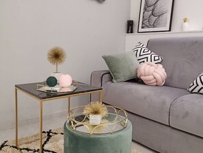 A modern living room with a grey sofa, a round coffee table with a gold frame, and decorative items including a dandelion and a pink spherical object. - Vernazza Luxury Apartment with AC (Vernazza)
