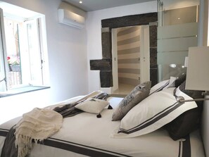 A bedroom with a bed, pillows, a bedside table, and a window. - Vernazza Luxury Apartment with AC (Vernazza)