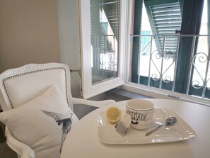 Une chaise blanche agrémentée d’un coussin décoratif, une table blanche sur laquelle se trouve un plateau avec une tasse, un citron et un sachet de thé.