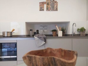 A kitchen with a built-in oven, a sink, and a countertop with various kitchen items. - Vernazza Luxury Apartment with AC (Vernazza)