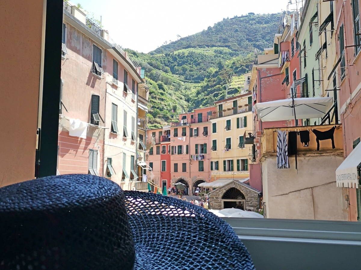 A view of a narrow street with colorful buildings, a mountain in the background, and a small archway.