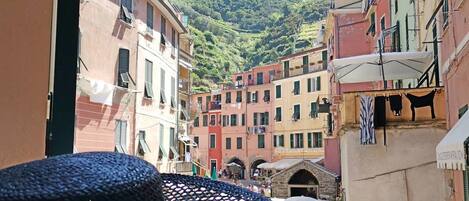 A view of a narrow street with colorful buildings, a mountain in the background, and a small archway.
