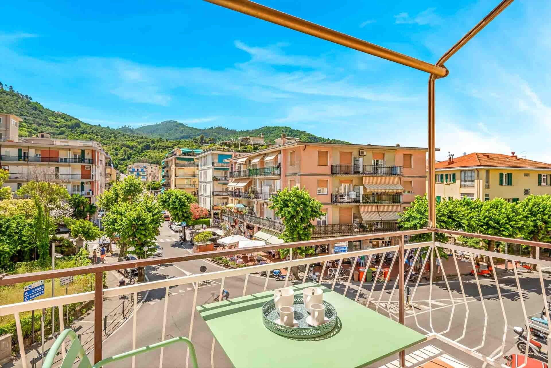 Ein Balkon mit Blick auf eine Straße, Gebäude und einen grünen Hügel im Hintergrund.