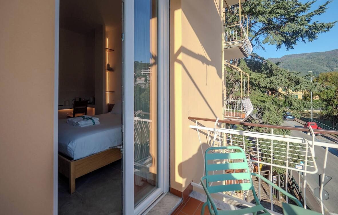 A balcony with a bed, a chair, and a view of the surrounding landscape.