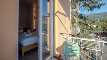 A balcony with a bed, a chair, and a view of the surrounding landscape.