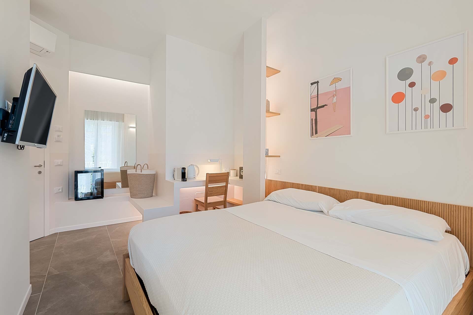 Ein Hotelzimmer mit Bett, Schreibtisch, Stuhl, Fernseher und Bildern an der Wand.