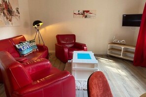 A living room with red leather sofas, a white coffee table, and a floor lamp. - Holiday apartment with 1 bedroom (Wyk auf Föhr)
