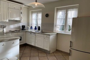 A kitchen with white cabinets, a dishwasher, a stove, and a refrigerator. - Strandstraße 28, half of the house on the left (Nieblum)