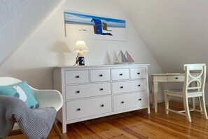 A room with a white dresser, a desk, a chair, and a lamp. - Holiday home in Oldsum with swimming pool (Oldsum)