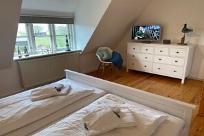 A bedroom with two beds, a TV, a dresser, and a window with a view. - Holiday home in Oldsum with swimming pool (Oldsum)