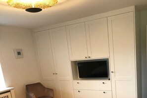 A room with a white wardrobe, a television mounted on it, and a chair. - Holiday home in Nieblum with swimming pool (Nieblum)