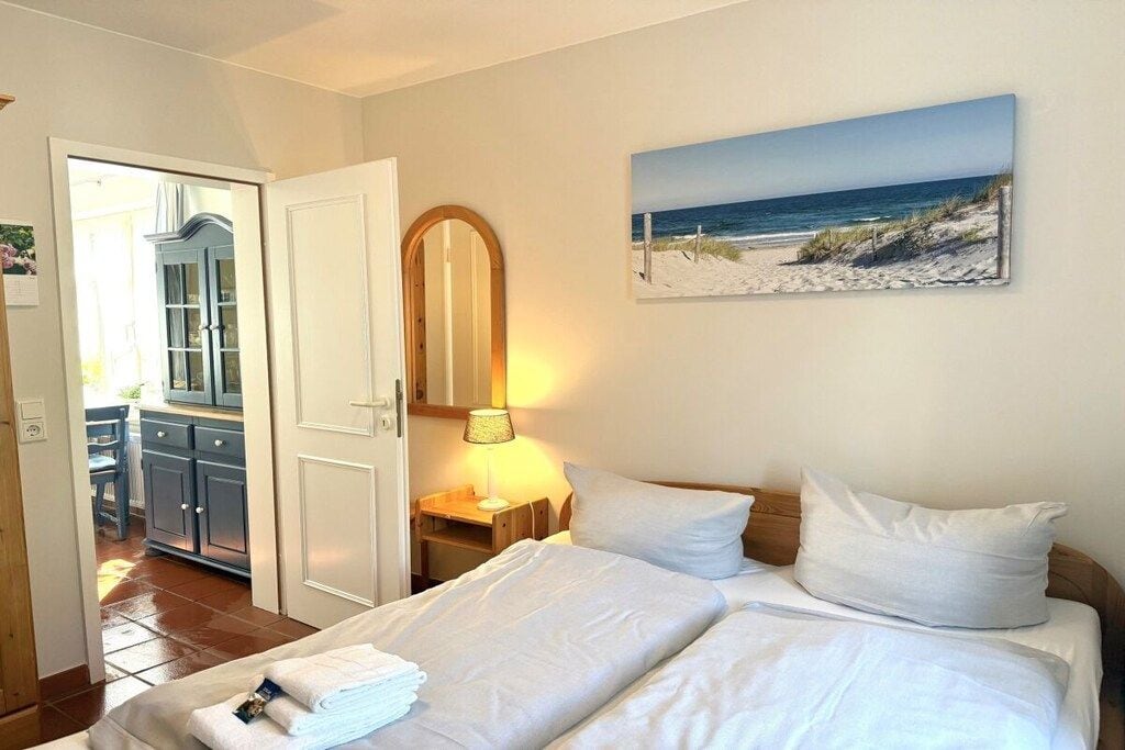 Ein Hotelzimmer mit einem Bett, einem Strandbild, einem Spiegel und einer Tür zu einem Badezimmer.