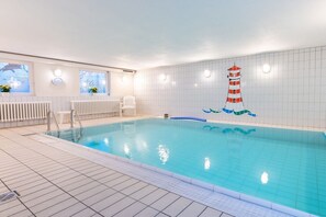 An indoor swimming pool with a tiled floor, a white chair, and a decorative lighthouse mural on the wall. - Holiday apartment with 1 bedroom (Wyk auf Föhr)