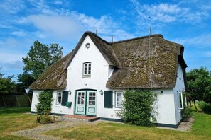 A white house with a thatched roof, a green door, and a small garden. - Deichhof Holiday Apartment 8 (Dunsum)
