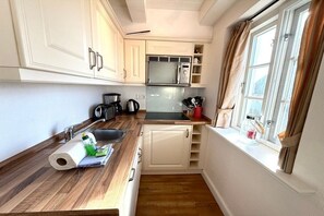 A compact kitchen with a microwave, kettle, and sink. - Deichhof Holiday Apartment 8 (Dunsum)