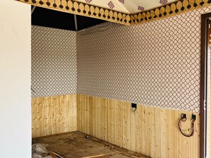 A room with a wooden floor, a patterned wall, and a door.