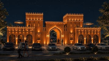 Imponente ingresso di un hotel con un'ampia arcata, diversi posti auto e una facciata ben illuminata.