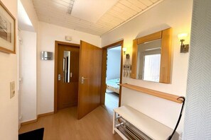 A hallway with wooden doors, a bench, and a wall-mounted mirror. - Holiday apartment with 2 bedrooms (Wyk auf Föhr)