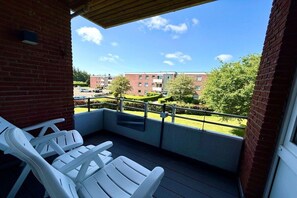 A balcony with white chairs, a view of a building, and a clear sky. - Holiday apartment with 2 bedrooms (Wyk auf Föhr)