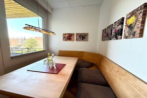 Un espace repas avec une table en bois, des bancs et des œuvres d’art accrochées au mur.