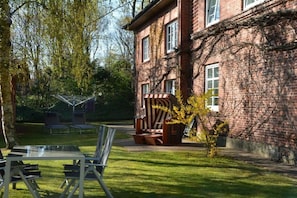 A brick building with a covered seating area and a small table with chairs. - Holiday apartment with 1 bedroom (Wyk auf Föhr)