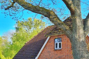 A red brick building with a sloped roof and a window. - Holiday apartment in Wyk on Föhr with Wi-Fi (Wyk auf Föhr)