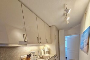A kitchen with white cabinets, a Siemens range hood, a coffee maker, and a sink. - Holiday apartment in Wyk on Föhr with Wi-Fi (Wyk auf Föhr)