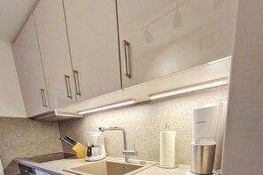 A modern kitchen with stainless steel appliances, a coffee maker, and a paper towel dispenser. - Holiday apartment in Wyk on Föhr with Wi-Fi (Wyk auf Föhr)