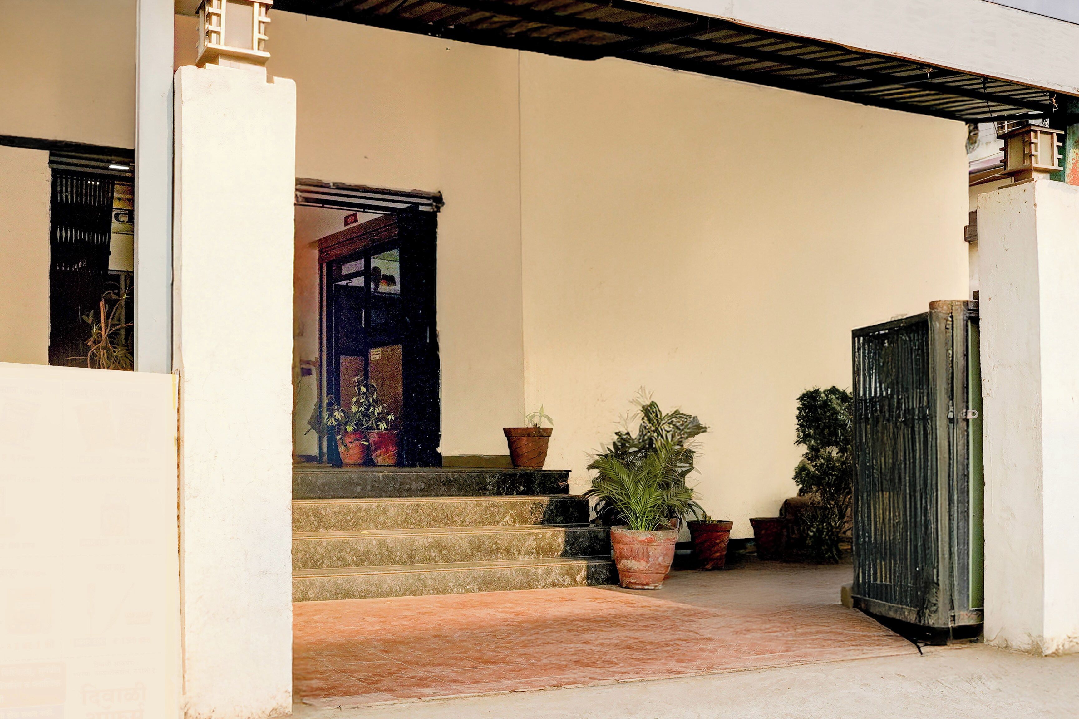Une entrée d’immeuble avec un escalier menant à une porte, le tout agrémenté de plantes en pot.