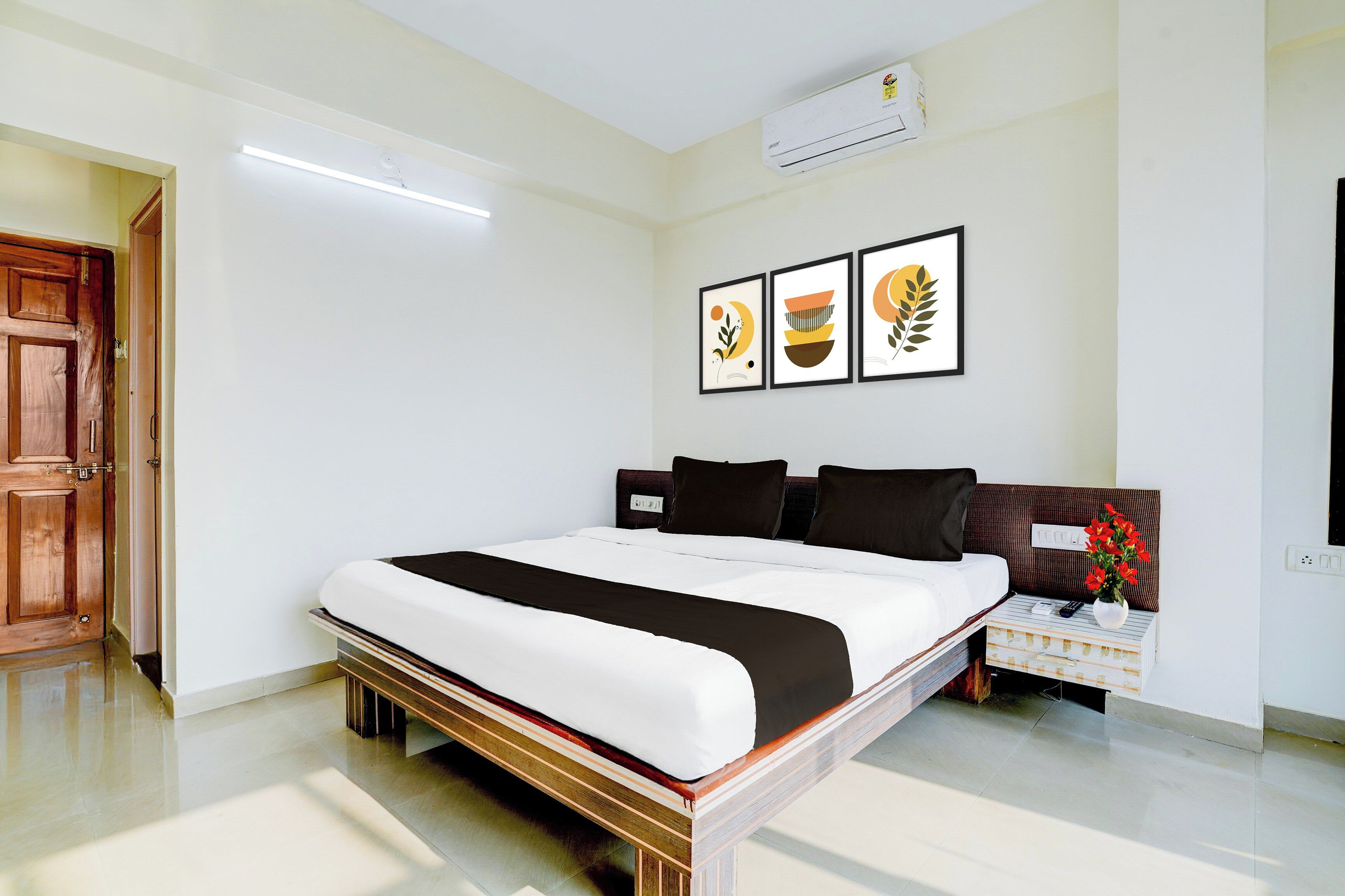 A hotel room with a bed, bedside table, and wall-mounted air conditioning unit.