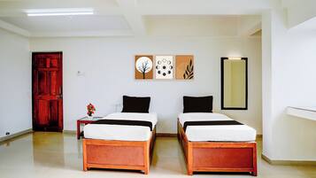 A hotel room with two beds, a wooden floor, a red door, and wall art.
