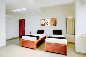 A room with two wooden beds, a red door, and wall art. - Super Hotel O Pachgaon Near Kolhapur (Kolhapur)
