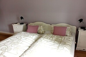 A double bed with a patterned bedspread, two bedside tables with lamps, and a headboard. - Holiday home in Föhr with 1 bedroom (Wyk auf Föhr)