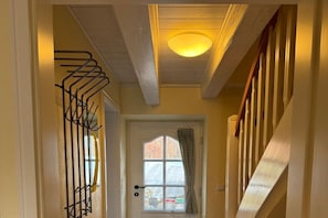A hallway with a door, a window with curtains, and a staircase. - Holiday home in Föhr with 1 bedroom (Wyk auf Föhr)