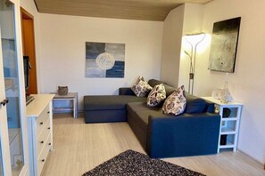 A modern living room with a sofa, a side table, a lamp, and a painting on the wall. - Holiday apartment in Föhr with 2 bedrooms (Wyk auf Föhr)