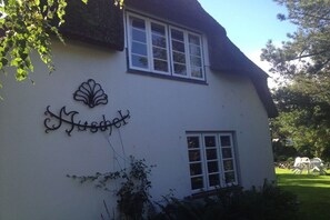 A white building with a black roof and a sign that reads 'Husky.' - Holiday apartment in Föhr with 2 bedrooms (Nieblum)