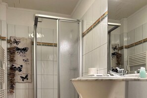 Un baño con ducha, lavamanos y espejo.