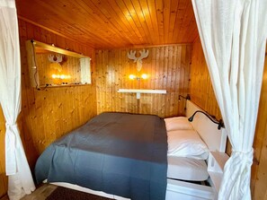 A wooden-paneled room with a bed, a mirror, and wall-mounted lights. - Chalet Felsenberg (CharmingStay), (Flumserberg Tannenheim), by Interhome (Flumserberg Tannenheim)