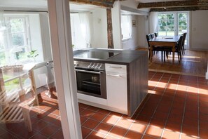 A kitchen with a central island, a dining area with a table and chairs, and a view of the outdoors through large windows. - Holiday home in Borgsum with swimming pool (Borgsum)
