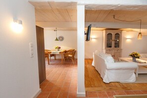 A room with a white sofa, a dining table with chairs, and a cabinet. - Holiday home in Borgsum with swimming pool (Borgsum)