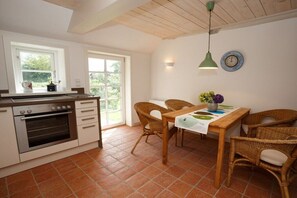 A kitchen with a built-in oven, a dining table with chairs, and a hanging pendant light. - Holiday home in Borgsum with swimming pool (Borgsum)