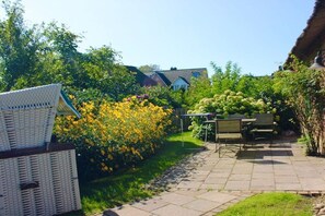 Ein Garten mit Korbmöbeln, einem Tisch und einer Bank.