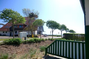 A residential area with a house, a green fence, and a clear sky. - Holiday apartment with 1 bedroom (Wyk auf Föhr)