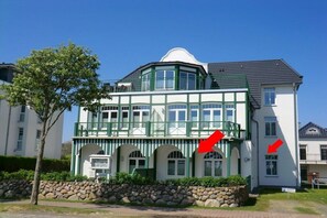 Ein zweistöckiges Gebäude mit Grün-Weiß-Farbgebung, mit Balkon und einer steinernen Fassade.