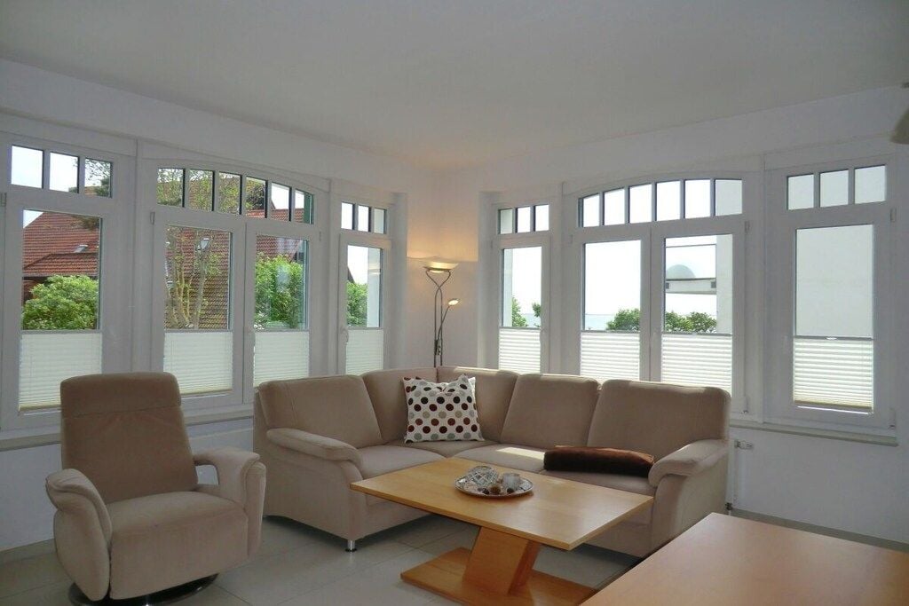 Een moderne woonkamer met een beige bank, een bijpassende fauteuil en een houten salontafel.