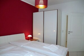 A hotel room with a bed, a wardrobe, a nightstand, and a lamp. - Holiday apartment with 1 bedroom (Wyk auf Föhr)