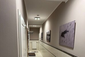 Een gang met een radiator, een deur en een aan de muur hangend kunstwerk.
