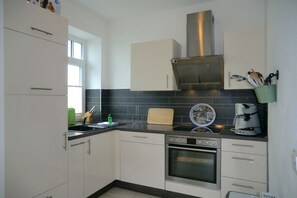 Een keuken met witte kasten, een roestvrijstalen afzuigkap, een koffiezetapparaat en een broodrooster.