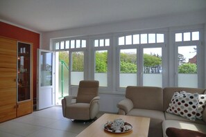 A living room with a sofa, armchairs, a coffee table, and a sliding glass door leading to an outdoor area. - Holiday apartment with 1 bedroom (Wyk auf Föhr)