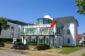 A two-story building with a balcony, stone wall, and a clear sky. - Holiday apartment with 1 bedroom (Wyk auf Föhr)